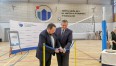 Prezydent Miasta Koszalina przecinający wstęgę na uroczystości w wyremontowanej hali sportowej koszalińskiego "Ekonoma"