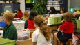Dzieci siedzące w klasie a przed nimi pudełka z nićmi i latarkami