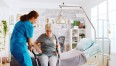 Pielęgniarka pomaga starszej Pani zejść z łóżka