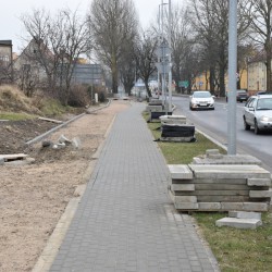 Budowa drogi rowerowej przy ul. Morskiej. Widać piasek oraz poukładane przy słupie płyty.