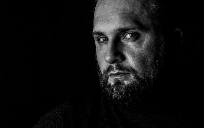 Fotografia w odcieni czerni i bieli przedstawia profil mężczyzny z brodą
