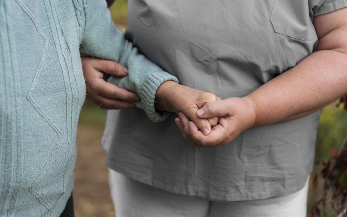 osoba prowadząca osobę niepełnosprawną pod rękę