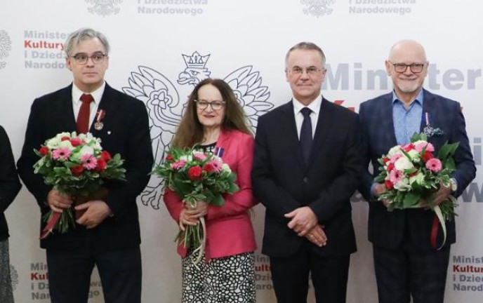 Na zdjęciu uczestnicy uroczystości wręczenia odznaczenia na tle ścianki opatrzonej logiem Ministerstwa Kultury i Dziedzictwa Narodowego