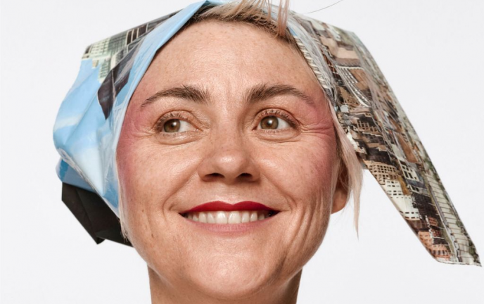 Zdjęcie przedstawia usmiechniętą kobietę w chuście na głowie na jasym tle.