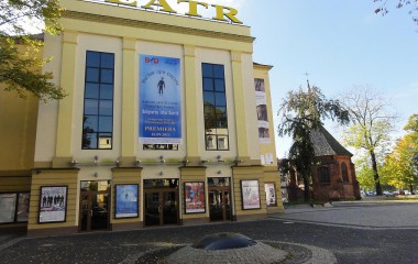 Budynek Bałtyckiego Teatru Dramatycznego w kolorze żółtym wraz ze zmodernizowanym w ramach projektu placem usytuowanym w obrębie budynku teatru. W pobliżu jest kilka drzew.