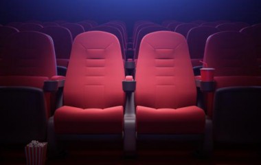 Zdjęcie przedstawia puste, czerwone fotele w sali kinowej