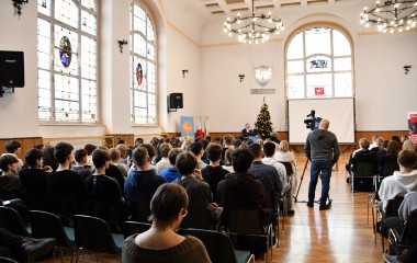 Na zdjęciu znajduje się sala w ILO w Koszalinie pełna młodzieży siedzącej na krzesłach. 