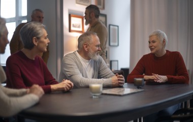 Grupa uśmiechniętych seniorów siedzących przy stole 