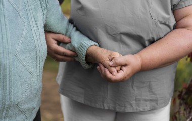 osoba prowadząca osobę niepełnosprawną pod rękę