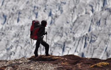 Zdjęcie przedstawia kobietę ubraną w odzież dla alpinistów na szczycie gór