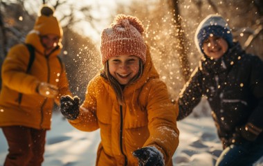 Na zdjęciu znajdują się uśmiechnięte dzieci, cieszące się zimową pogodą. 